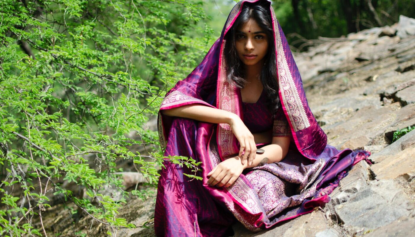 Indian girl with olive skin sitting on the rock in the forest